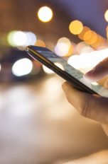 Männerhände mit iPhone vor regem Straßentreiben