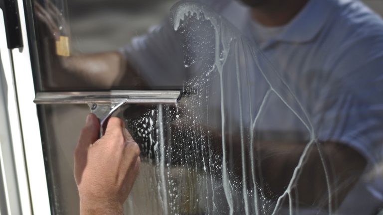 Mit einem Gummiabzieher entfernen Sie überschüssiges Wasser von der Fensterscheibe. Fenster putzen mit dem Gummiabzieher