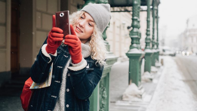 Eine Person ist im Winter draußen und macht mit dem Handy Fotos.nter draußen und macht mit dem Handy Fotos.