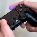 Hand bedient eine Sony PlayStation 4 über einen Controller.