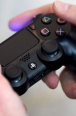 Hand bedient eine Sony PlayStation 4 über einen Controller.