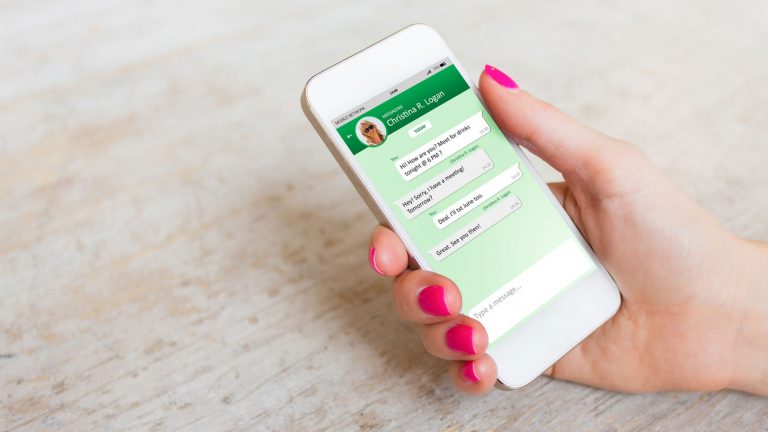 Mit WhatsApp erreichen Sie viele Kontakte. Frauenhand mit Smartphone und geöffnetem WhatsApp Messenger