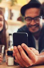 Gruppe schaut erfreut auf Smartphone.