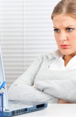 Frau blickt verärgert auf Notebook.