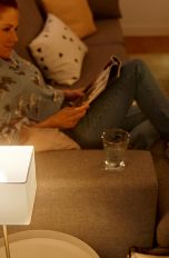 Frau sitzt auf Sofa mit eingeschalteter Lampe