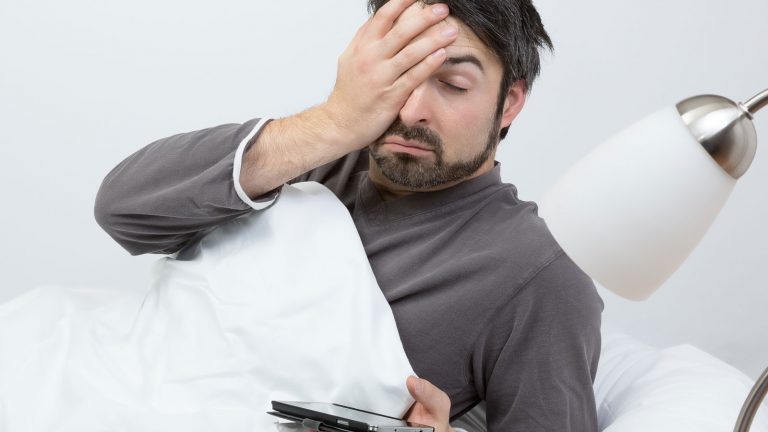 Mann im Bett mit Smartphone in der Hand