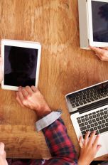 Familie mit Apple-Geräten am Tisch nutzt Apple-Familienfreigabe