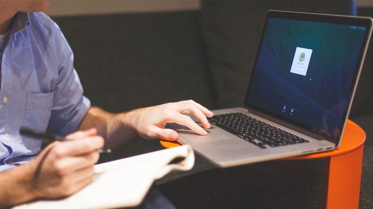 Mac ist langsam: Festplatte überprüfen Person mit Macbook und Notizbuch auf der Couch