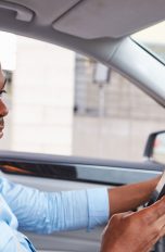 Ein Autofahrer bedient eine App auf seinem Smartphone.