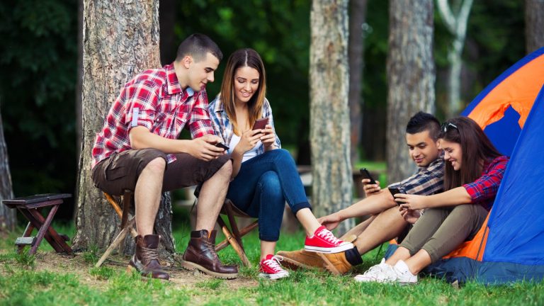 Gruppe mit Smartphones beim Camping