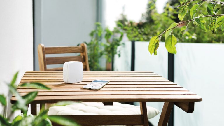 HomeKit unterwegs nutzen Zuhause Elgato Eve Weather mit iPhone auf Gartentisch