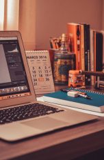 Photoshop auf einem Macbook Air auf einem Tisch mit Schreibtischutensilien