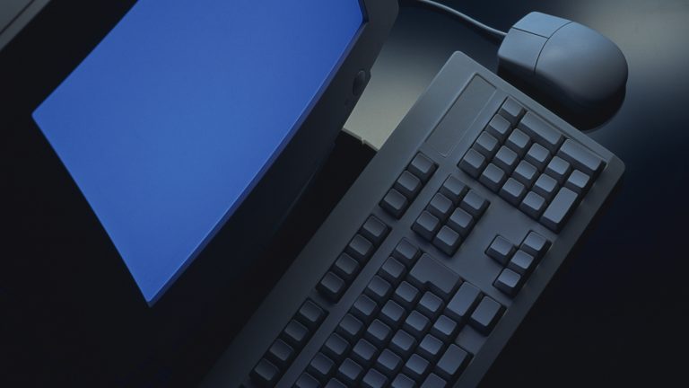 Sicht von oben auf einen Röhren-Monitor mit Tastatur und Maus auf dem Tisch