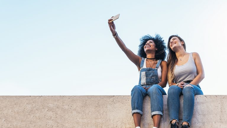 Zwei junge Frauen machen Selfie mit dem iPhone und wollen es per Mail-Anhang versenden Zwei junge Frauen machen Selfie mit dem iPhone und wollen es per Mail-Anhang versenden