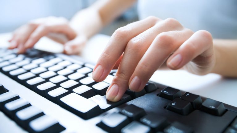 Windows-Tastatur mit Hand, ein Finger drückt die Return-Taste