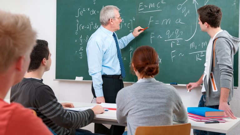 Schüler im Matheunterricht lösen Aufgabe an der Tafel