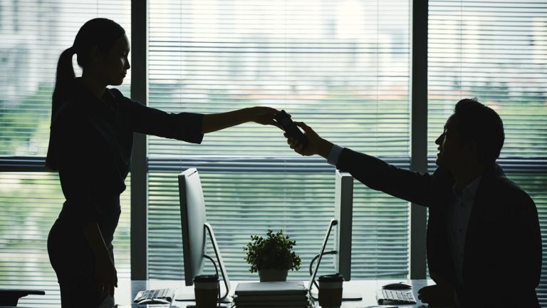 Frau übergibt Smartphone an Kollegen