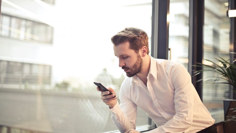 Mann schaut angestrengt auf sein Smartphone Mann schaut angestrengt auf sein Smartphone