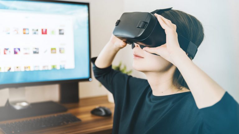 Frau mit VR Brille sitzt vor PC