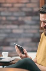 Junger Mann nutzt im Café den Google Authenticator auf mehreren Geräten