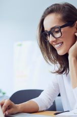 Windows 10 Sprache ändern: Frau sitzt am Laptop und lächelt