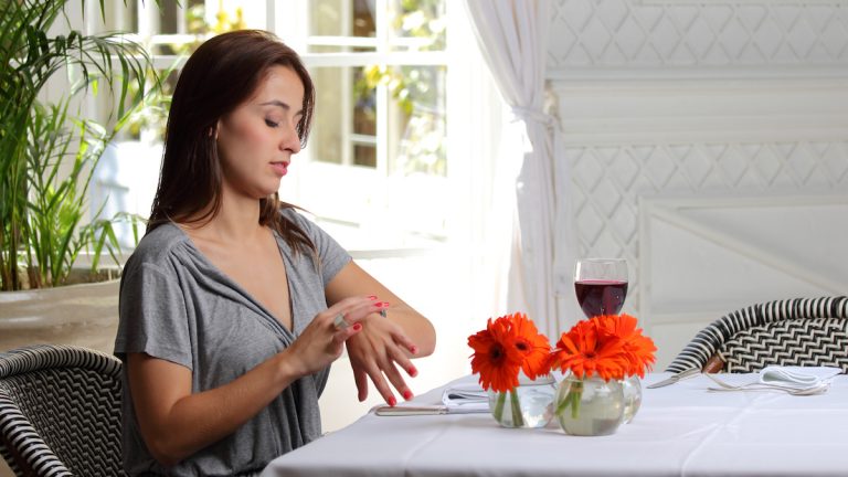 Google Kalender in Outlook: warten Junge Frau sitzt wartend im Restaurant und schaut auf die Uhr