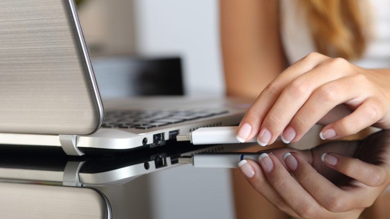 Hand zieht USB-Stick vom Laptop от