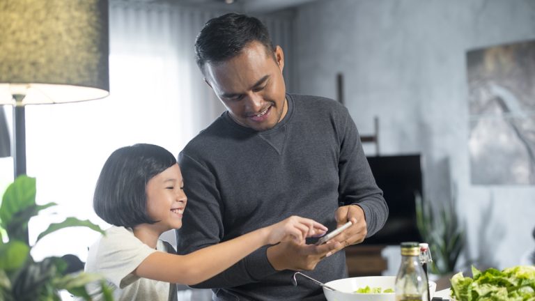 In-App-Käufe deaktivieren: Kindersicherheit Kind und Vater benutzen ein Smartphone