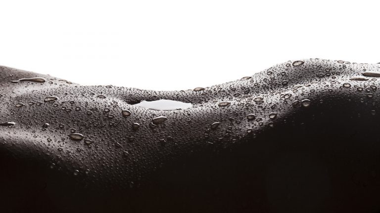 Schwarz-Weiß-Aufnahme Bauch einer Frau mit Wasser im Bauchnabel