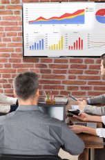 PowerPoint Wasserzeichen einfügen: Frau steht vor Präsentation und zeigt darauf