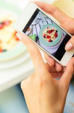 Instagram-Daten schützen: Junge Frau fotografiert ihr Essen mit dem Smartphone