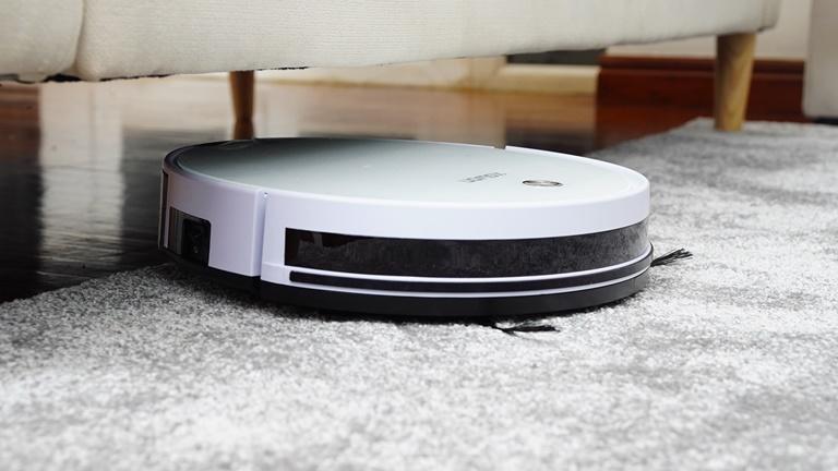 Ein Staubsaugerroboter wechselt zwischen Teppich und Parkettboden Ein Staubsaugerroboter wechselt zwischen Teppich und Parkettboden
