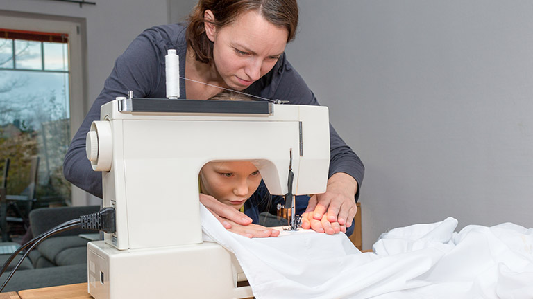 Mutter zeigt Mädchen das Nähen an der Nähmaschine