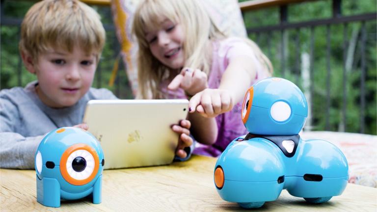 Mädchen und Junge spielen mit Roboter Dot Mädchen und Junge spielen mit Roboter Dot