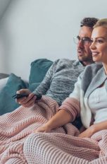 Paar sitzt auf der Couch und schaut Fernsehen übers Internet