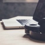 Laptop und Bluetooth-Kopfhörer auf Holztisch