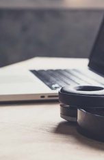 Laptop und Bluetooth-Kopfhörer auf Holztisch
