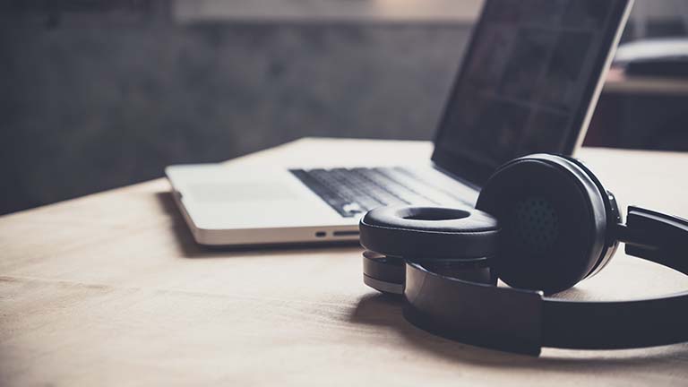 Laptop und Bluetooth-Kopfhörer auf Holztisch