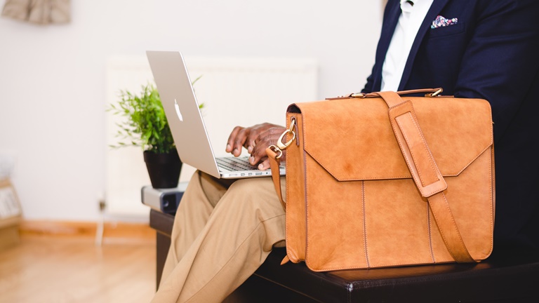 Mann hat MacBook auf dem Schoß