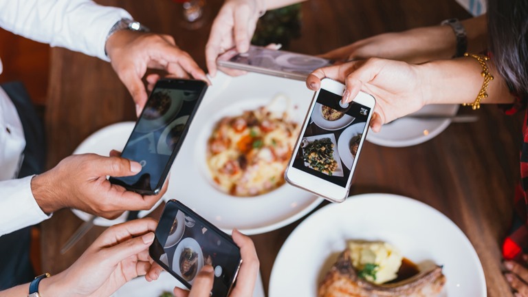 Freunde essen Pizza, schießen dabei Fotos und machen Video