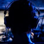 Eine Frau mit Kopfhörern nimmt ein Let’s Play als Screencast auf