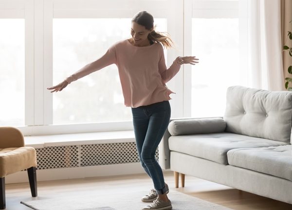 Eine Frau tanzt zu Musik aus ihrem Sonos-Lautsprecher im Wohnzimmer