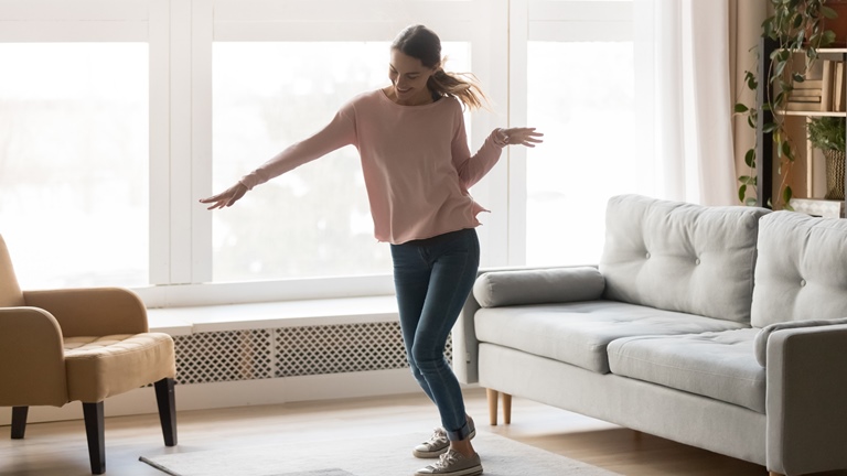 Eine Frau tanzt zu Musik aus ihrem Sonos-Lautsprecher im Wohnzimmer