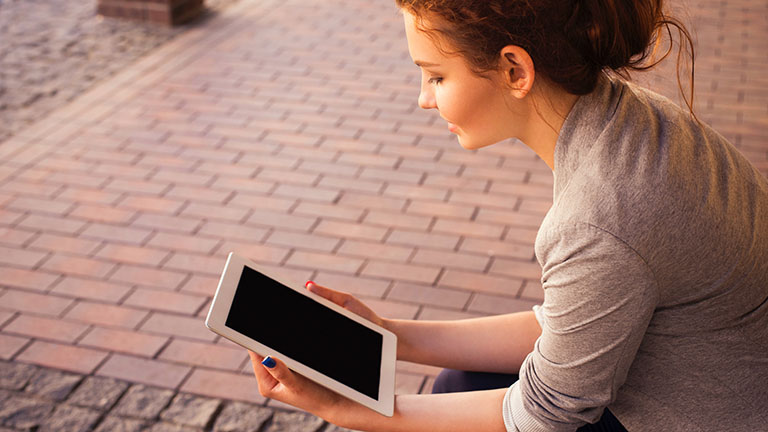 Frau tippt lächelnd auf Tablet