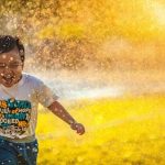 Junge läuft lachend durch Sommerregen