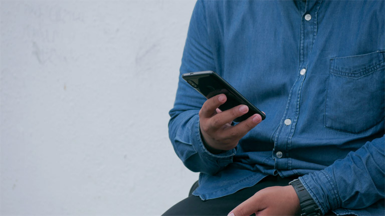 Miele-Geschirrspüler: Das bedeuten Fehlercode F24 und Co. Mann sucht in seinem Smartphone nach Informationen.
