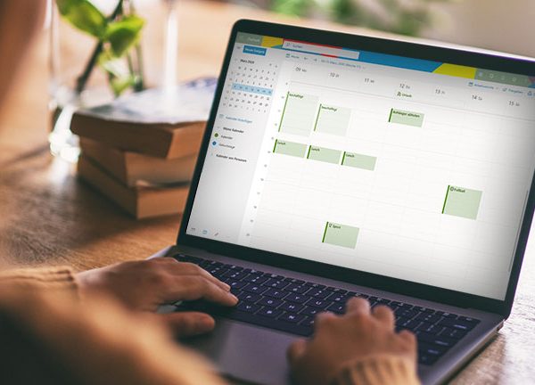 Eine Person blickt auf ein Notebook. Dort ist die Kalenderansicht von Microsoft Outlook geöffnet.