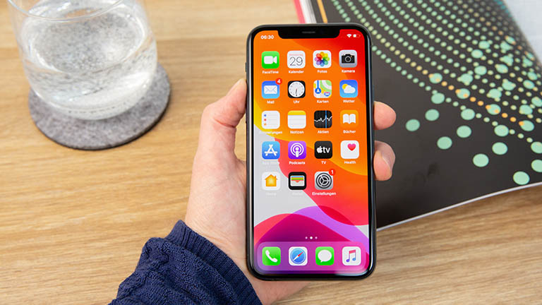 Eine Person hält das iPhone 11 in der Hand. Auf dem Display ist der Home-Bildschirm zu sehen.