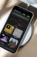 Ein iPhone auf einer kabellosen Ladestation. Auf dem Bildschirm ist die neue Auswahl der Widgets zu sehen.