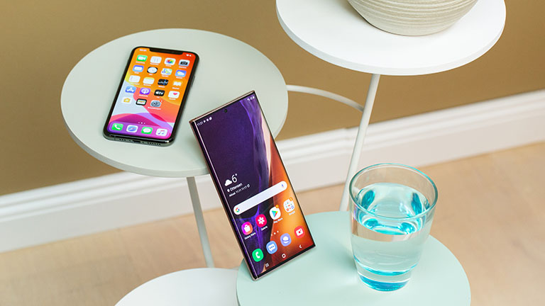 Android vs. iOS Ein iPhone 11 liegt auf einem Tisch. Ein Samsung Galaxy Note 20 Ultra lehnt dagegen.